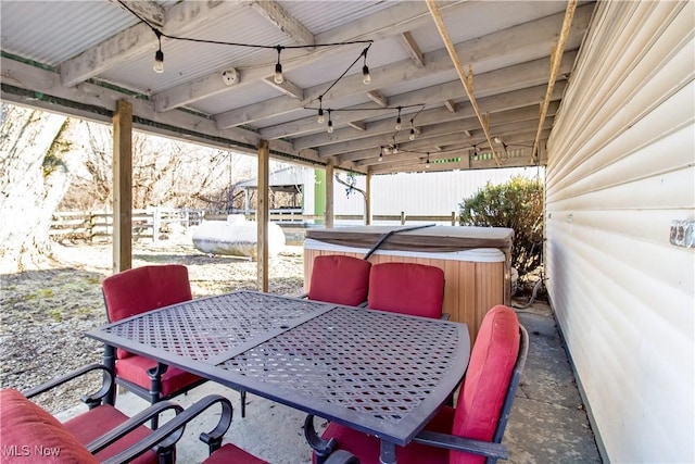 view of patio with a hot tub, outdoor dining area, and fence