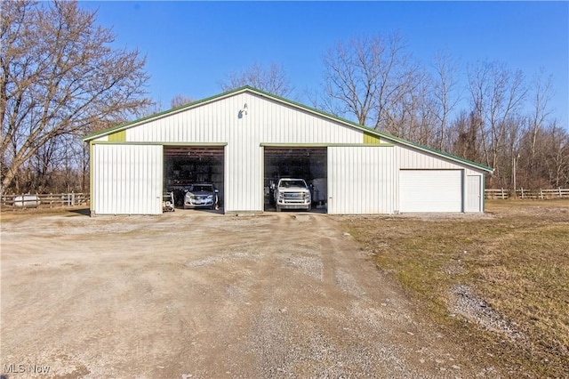 detached garage featuring fence and dirt driveway