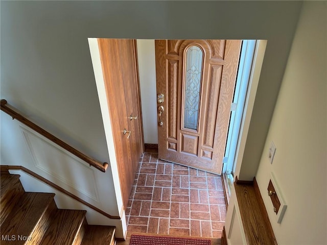 entryway with stairway, baseboards, and brick floor