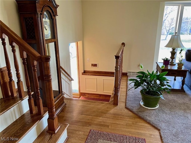 interior space with a decorative wall, a wainscoted wall, stairs, and wood finished floors