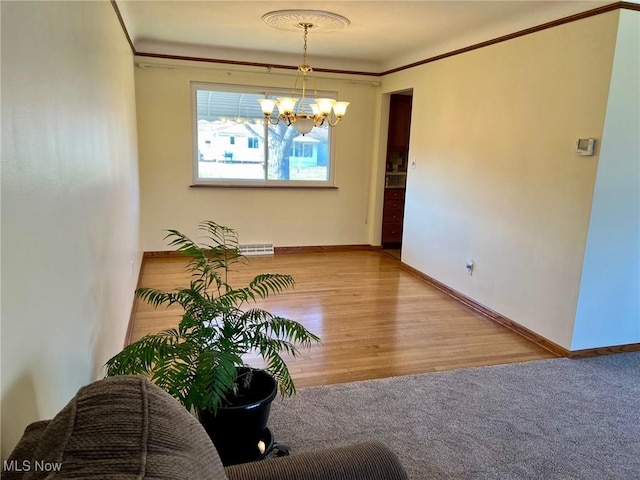 dining space featuring wood finished floors, baseboards, a chandelier, and crown molding