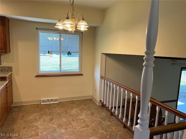 unfurnished dining area with baseboards, visible vents, and a chandelier