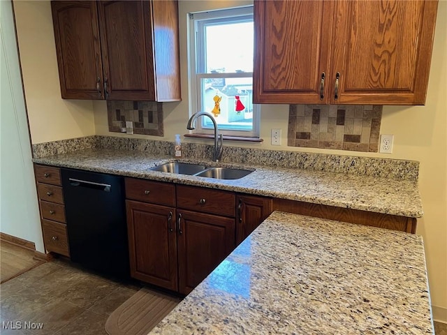 kitchen with a sink, decorative backsplash, light stone counters, and black dishwasher