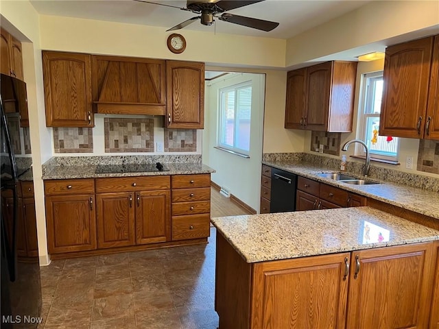 kitchen with ceiling fan, custom range hood, light stone counters, black appliances, and a sink