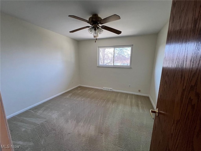 carpeted empty room with a ceiling fan, baseboards, and visible vents