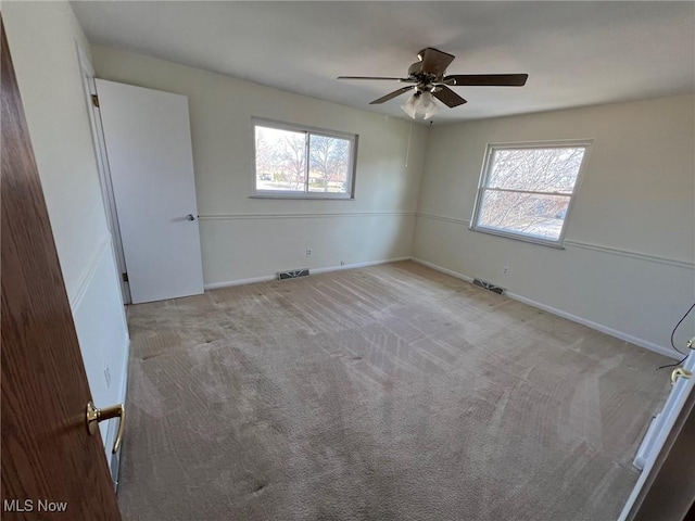 unfurnished room with a ceiling fan, visible vents, a wealth of natural light, and light carpet