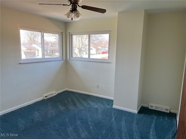 spare room featuring visible vents, dark carpet, baseboards, and a ceiling fan