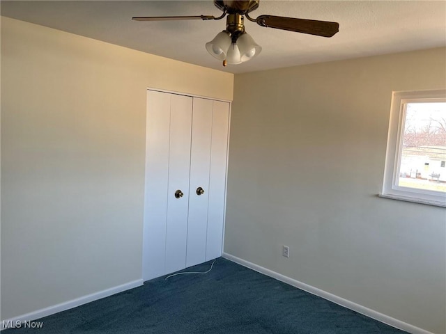 unfurnished bedroom featuring a closet, dark carpet, baseboards, and ceiling fan