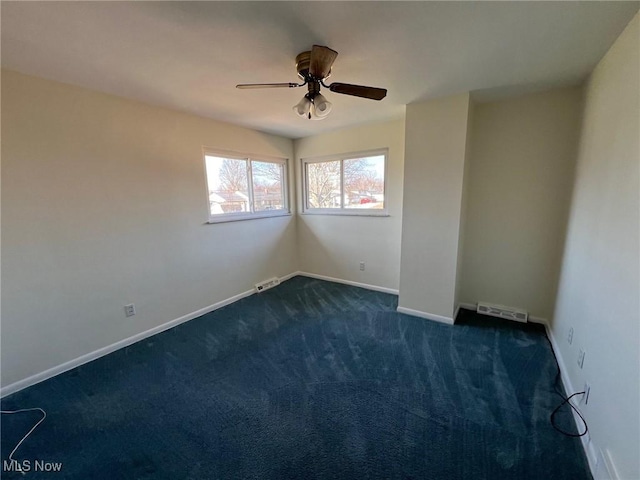 unfurnished room featuring baseboards, visible vents, dark colored carpet, and ceiling fan