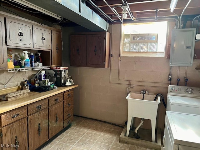 washroom featuring concrete block wall, electric panel, cabinet space, independent washer and dryer, and a sink