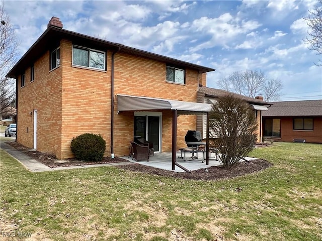 rear view of property featuring brick siding, a lawn, a chimney, and a patio