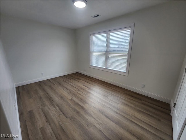 unfurnished room featuring visible vents, baseboards, and wood finished floors