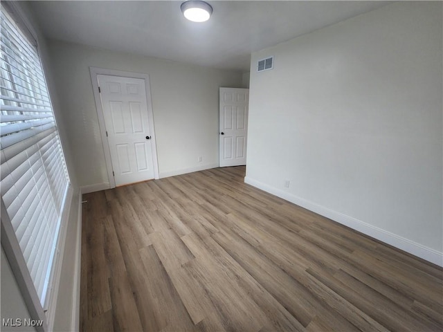 unfurnished bedroom with visible vents, baseboards, and wood finished floors