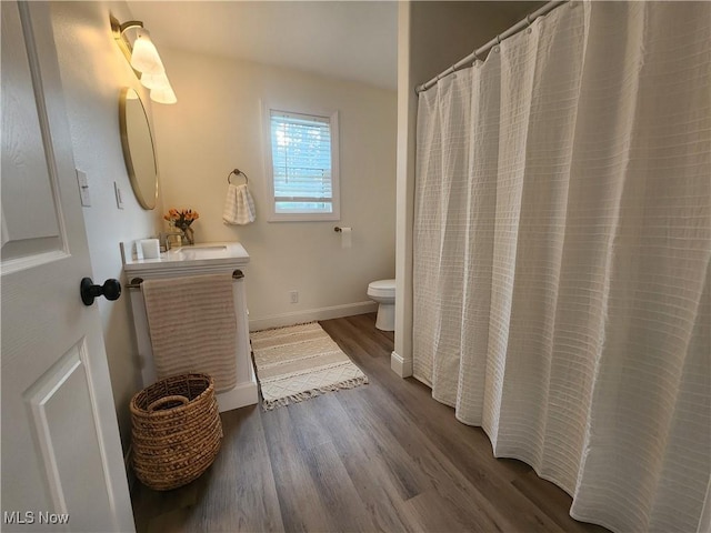 full bathroom featuring baseboards, toilet, wood finished floors, and vanity