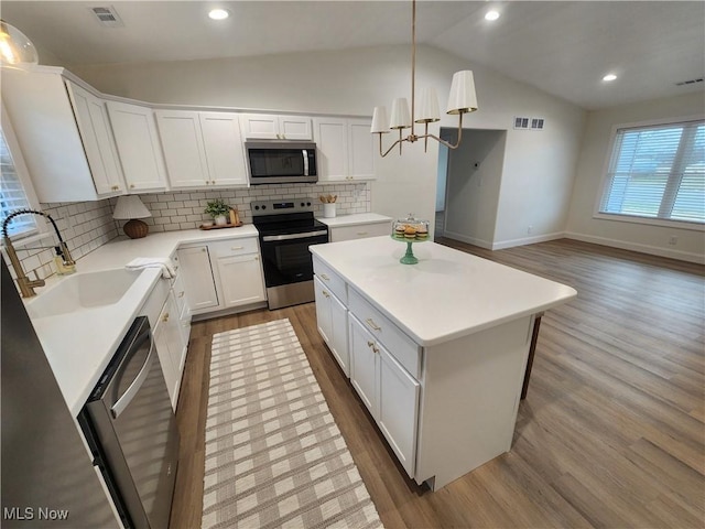 kitchen with a sink, lofted ceiling, visible vents, and stainless steel appliances