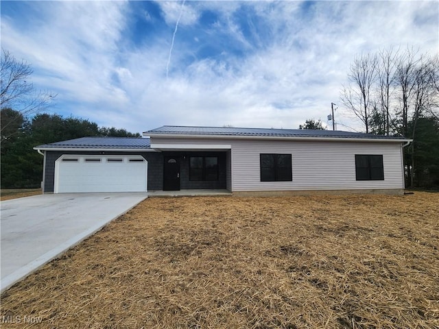 ranch-style house with an attached garage, metal roof, and driveway