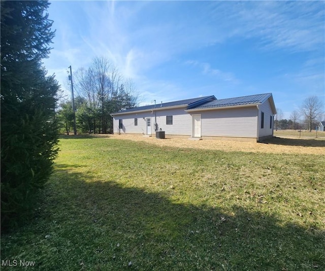 rear view of property with metal roof, a yard, and a standing seam roof