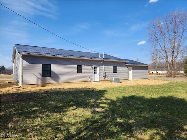 back of house with a yard, central AC, and metal roof