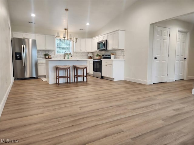 kitchen featuring stainless steel appliances, light wood-style flooring, decorative backsplash, and white cabinetry