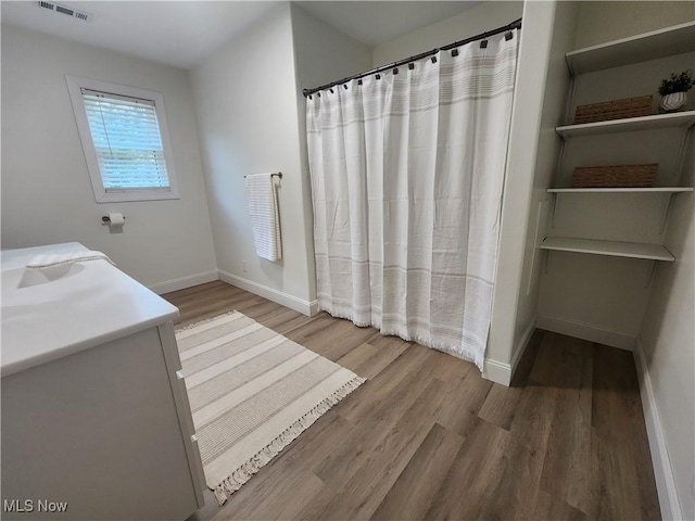 full bathroom featuring visible vents, baseboards, a shower with curtain, and wood finished floors