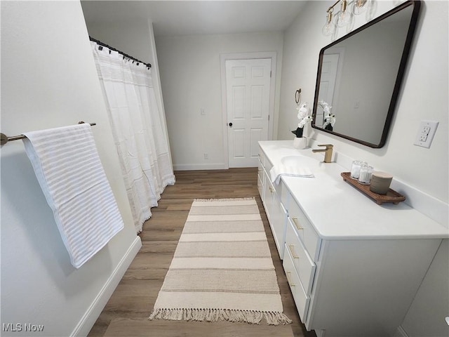 bathroom featuring baseboards, wood finished floors, and vanity