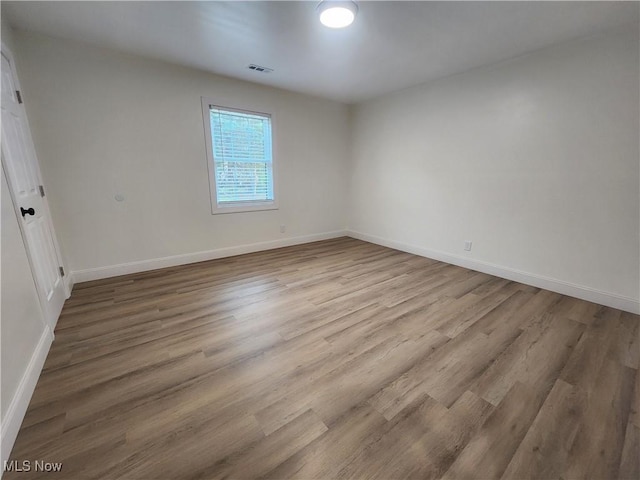 unfurnished room featuring visible vents, baseboards, and wood finished floors