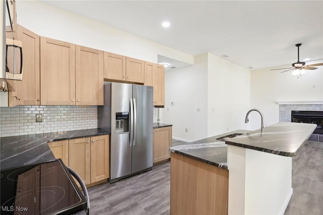 kitchen with electric range, stainless steel refrigerator with ice dispenser, dark stone countertops, tasteful backsplash, and ceiling fan