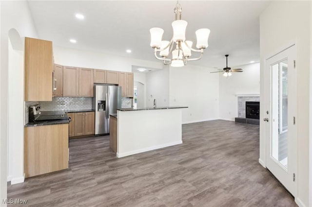 kitchen featuring dark countertops, dark wood-type flooring, decorative backsplash, ceiling fan with notable chandelier, and stainless steel appliances