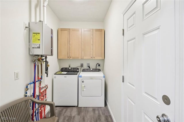 clothes washing area featuring wood finished floors, cabinet space, baseboards, and washer and clothes dryer