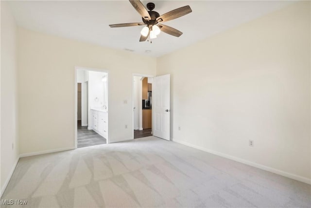 unfurnished bedroom with ensuite bath, light colored carpet, and baseboards