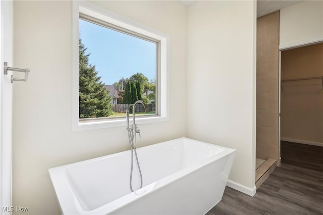 bathroom with wood finished floors, baseboards, and a freestanding bath