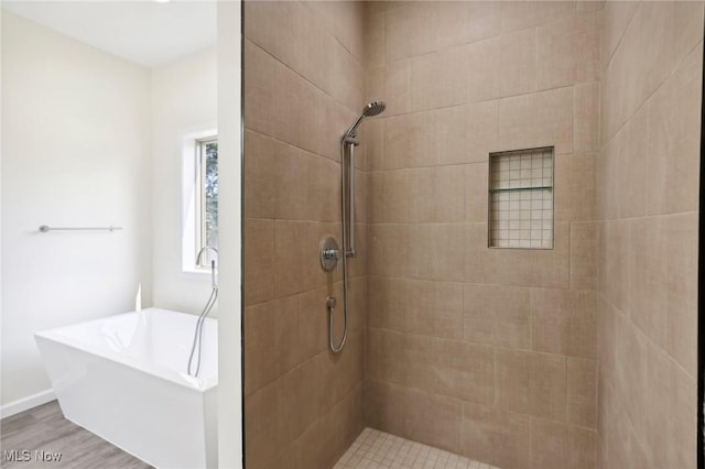 bathroom featuring a freestanding tub, wood finished floors, and a tile shower