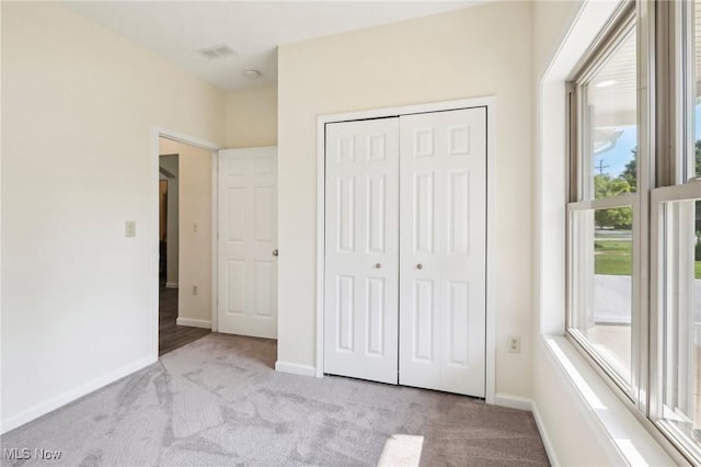 unfurnished bedroom featuring carpet, baseboards, and a closet