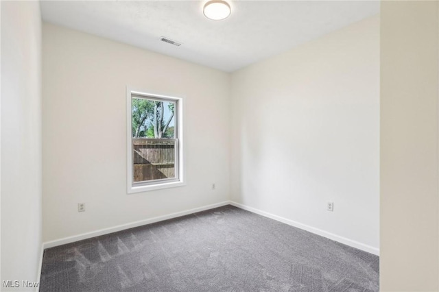 spare room featuring visible vents, dark carpet, and baseboards