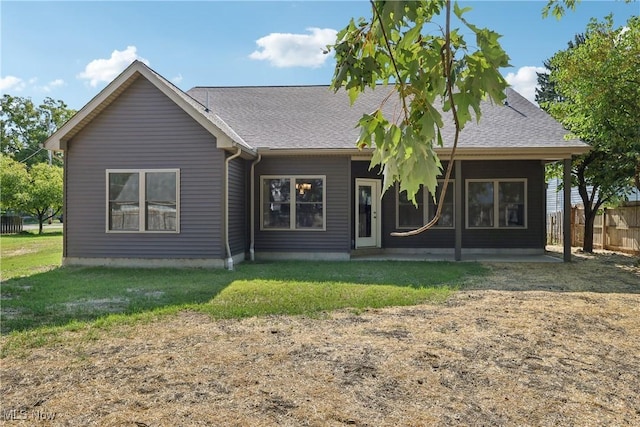 back of house with a lawn, roof with shingles, and fence