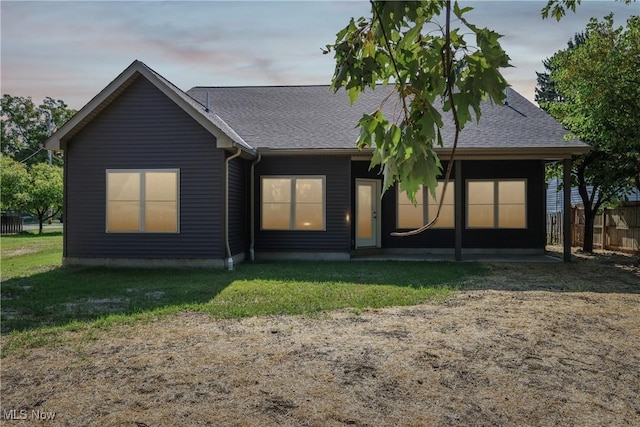 rear view of house featuring a yard, roof with shingles, and a patio area