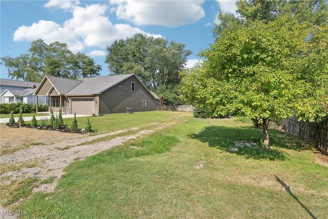 view of yard with fence, a garage, and driveway