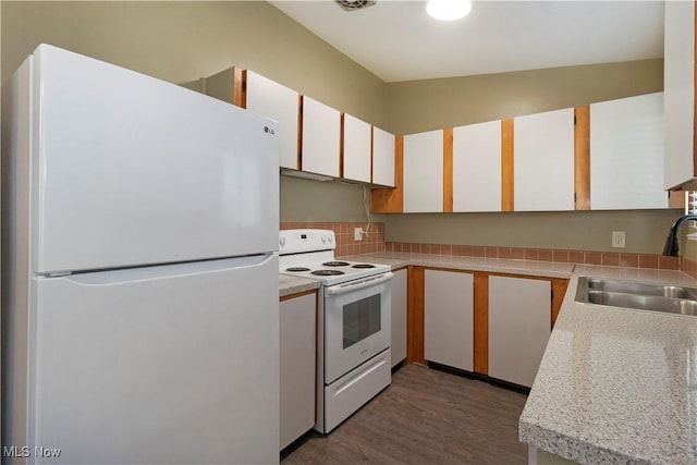 kitchen featuring white appliances, wood finished floors, a sink, light countertops, and white cabinetry