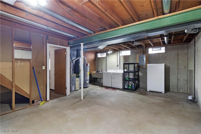 below grade area featuring electric panel, a sink, freestanding refrigerator, gas water heater, and separate washer and dryer