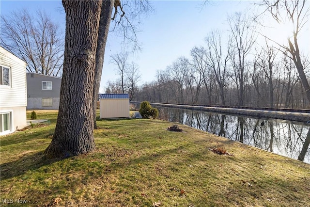 view of yard featuring a storage unit, a water view, and an outbuilding