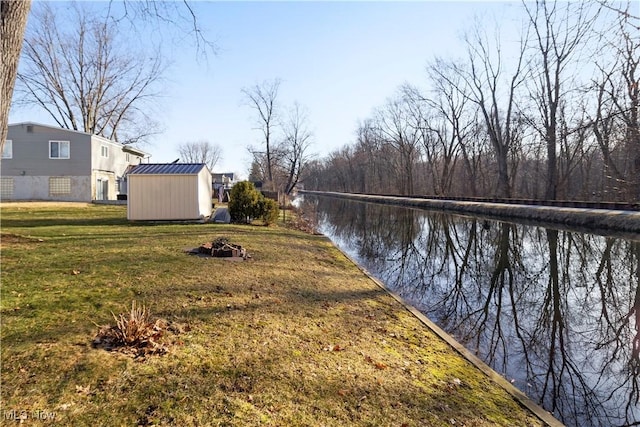 view of yard with an outdoor structure, a fire pit, a water view, and a shed