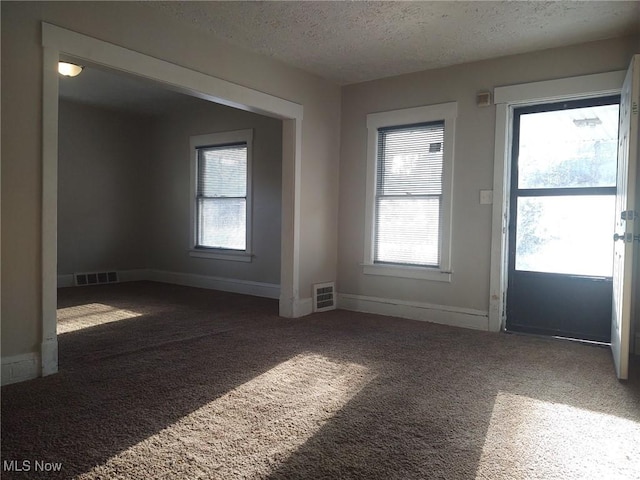 empty room featuring visible vents, a textured ceiling, and carpet