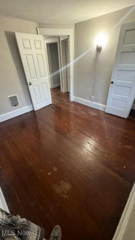 interior space featuring dark wood-style floors, visible vents, and baseboards