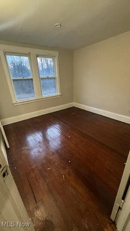 spare room featuring baseboards and hardwood / wood-style floors