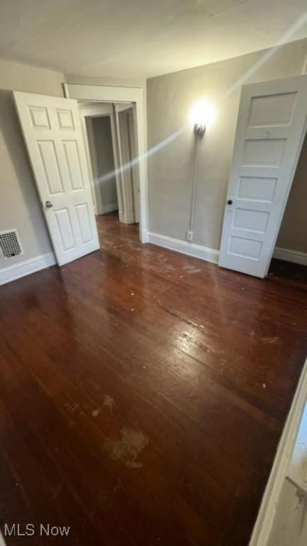 interior space with visible vents, dark wood-type flooring, and baseboards