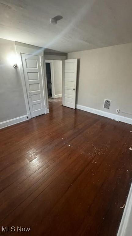 interior space featuring visible vents, dark wood-type flooring, and baseboards