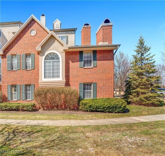 view of home's exterior featuring a yard, brick siding, and a chimney