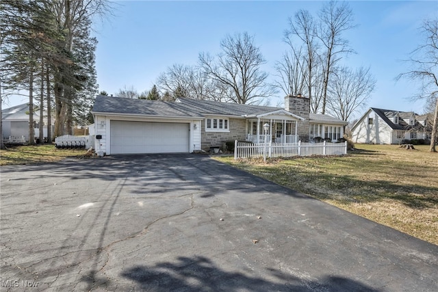 view of front of property with stone siding, driveway, a chimney, and an attached garage