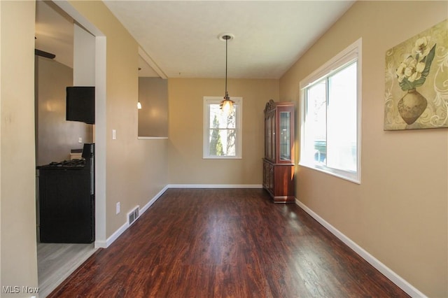 unfurnished dining area with wood finished floors, visible vents, and baseboards