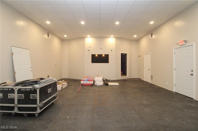 interior space with a drop ceiling, recessed lighting, concrete flooring, and a high ceiling